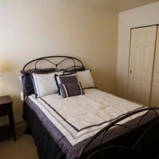 A simple bedroom with a neatly made bed and a lamp.