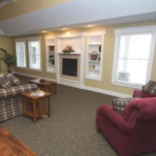 A cozy living room with sofas facing a fireplace, surrounded by built-in shelves and large windows.