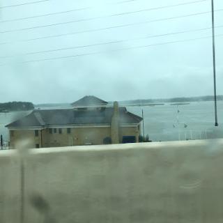 A view of a house by the water on a cloudy, rainy day.
