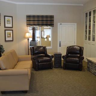 A cozy living room with a sofa, two leather chairs, and elegant decor.