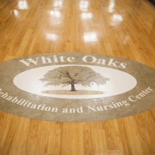The logo of White Oaks Rehabilitation and Nursing Center displayed on the floor.