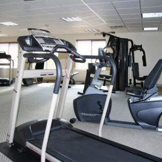 An image of a gym with various exercise equipment including a treadmill and stationary bike.