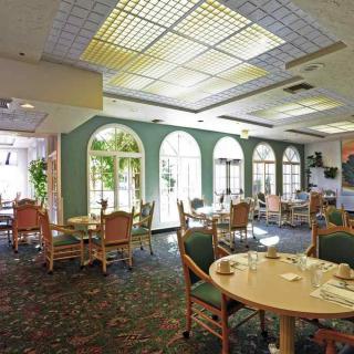 A bright and spacious dining area with tables and chairs arranged under large windows.