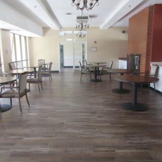 An empty dining area with wooden floors and chandelier lighting.