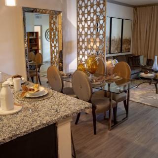 A modern open-concept dining and living area with a decorative screen, stylish furniture, and elegant table settings.