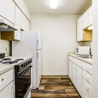 A compact modern kitchen with white cabinets and essential appliances.