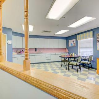 Retro-style kitchen with checkered flooring and blue walls, featuring dining table and chairs.
