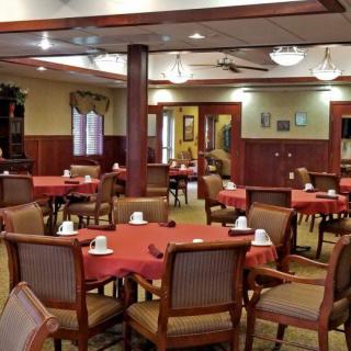 An empty dining room with neatly arranged tables and chairs, featuring a warm and inviting decor.