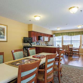 A well-lit dining and kitchen area with wooden furniture and cabinetry.