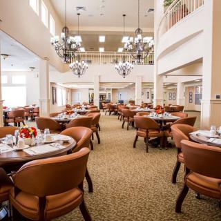 An elegant dining area with neatly arranged tables and chairs under grand chandeliers.