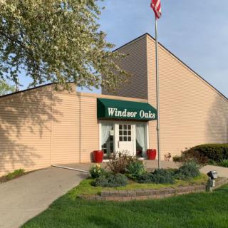 Entrance of Windsor Oaks with a flagpole and landscaped greenery.