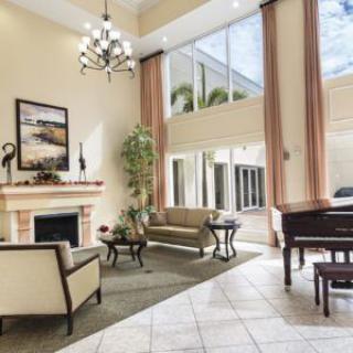 A spacious and elegant lobby with a fireplace, comfortable seating, large windows, and a grand piano.
