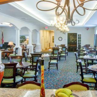 A well-lit dining area with elegant chandeliers and neatly arranged tables and chairs.