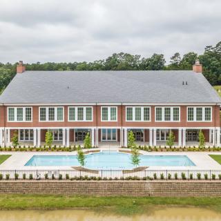 A large brick mansion with an outdoor pool and manicured landscaping.