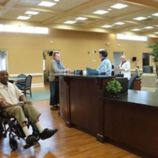 A reception area with people interacting, including a person in a wheelchair.