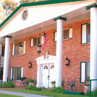 A two-story brick house with prominent white columns and an American flag displayed at the entrance.