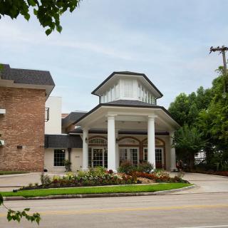 A building entrance featuring columns and landscaped surroundings.