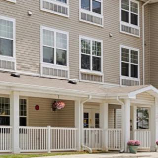 A multi-story residential building with a white porch and multiple windows.