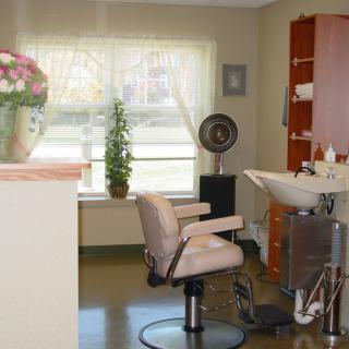 A cozy and well-organized hair salon interior with a styling chair, sink, and various hairdressing equipment.