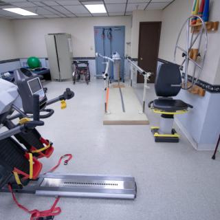 A rehabilitation room equipped with various exercise machines and therapy tools.