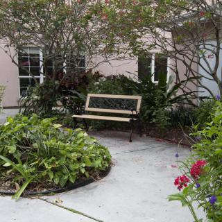 A peaceful garden setting with a bench surrounded by lush greenery and colorful flowers.