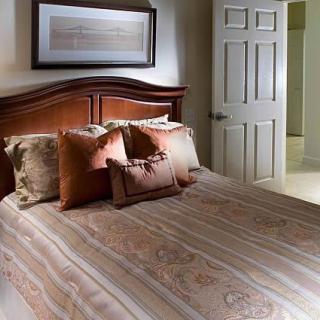 A cozy bedroom featuring a neatly made bed with multiple pillows and a wooden headboard.