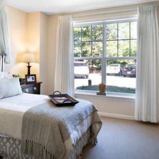 A cozy bedroom with large window and elegant decor.