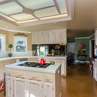 A bright, modern kitchen featuring a central island with a stovetop and white cabinetry.