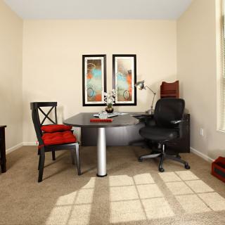 A modern office space with a desk, two chairs, and framed artwork on the wall.