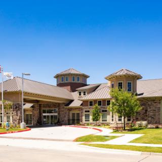A modern building with a grand entrance and well-maintained landscape.