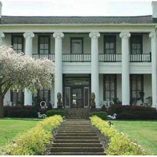 A historic mansion with large columns and a beautifully landscaped garden.