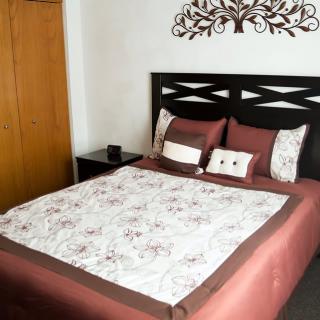 A neatly arranged bedroom with a decorative headboard and floral quilt.