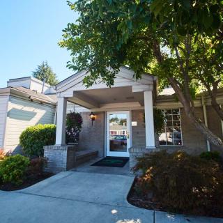 A building entrance with a covered entryway, surrounded by trees and landscaping.