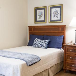 A cozy bedroom with a neatly made bed, nightstand, and decorative wall art.