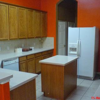 A modern kitchen featuring wooden cabinets and an orange accent wall.