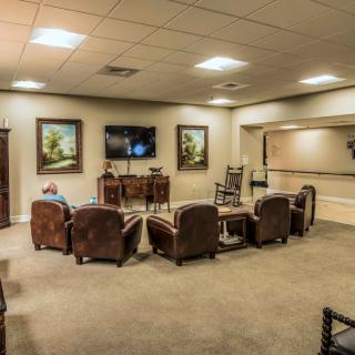 A cozy lounge with leather chairs and large paintings on the walls.