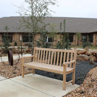 A wooden bench situated in a serene garden setting, surrounded by plants and a walkway.