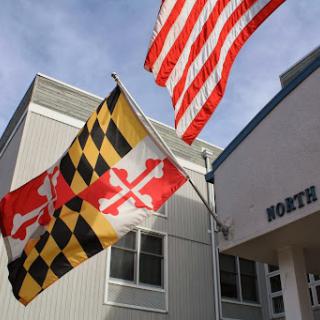 Flags of Maryland and the United States flying together in front of a building.