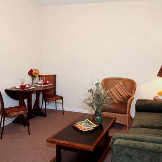 A cozy living room featuring a sofa, coffee table, and a small dining table set.