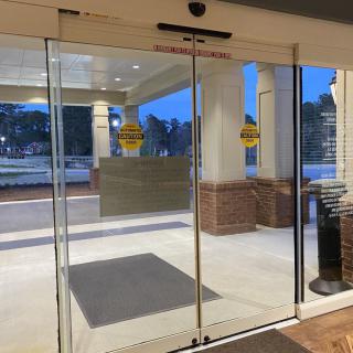 An automatic glass door at a building entrance, with 'No Entry' signs visible.