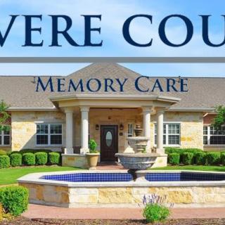 Exterior view of a memory care facility with a central fountain.