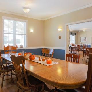 A cozy dining room with autumn-themed decor, featuring a large wooden table and chairs.