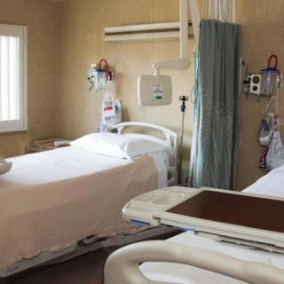 A clean and organized hospital room with two medical beds divided by a curtain.