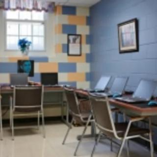 A small computer lab with desks and laptops arranged in a row.