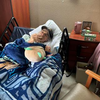 A patient resting in a hospital bed, covered with a blanket.