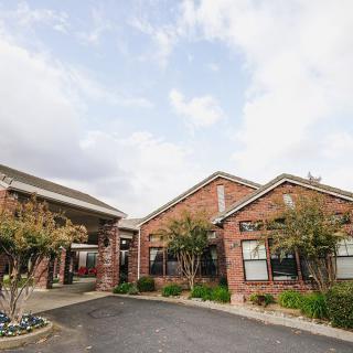 A brick building with an entrance and surrounding trees under a cloudy sky.