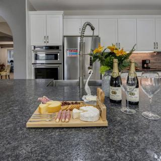 A modern kitchen with a cheese platter and wine bottles on the countertop.
