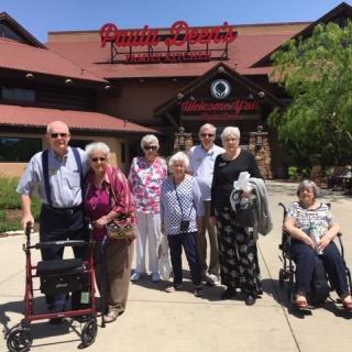 A group of people standing outside a restaurant on a sunny day.