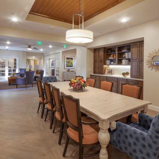 A modern dining room with a large table and stylish chairs, featuring warm lighting and wooden accents.