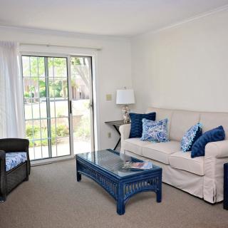 A cozy living room with a beige couch, blue coffee table, and sliding glass door.